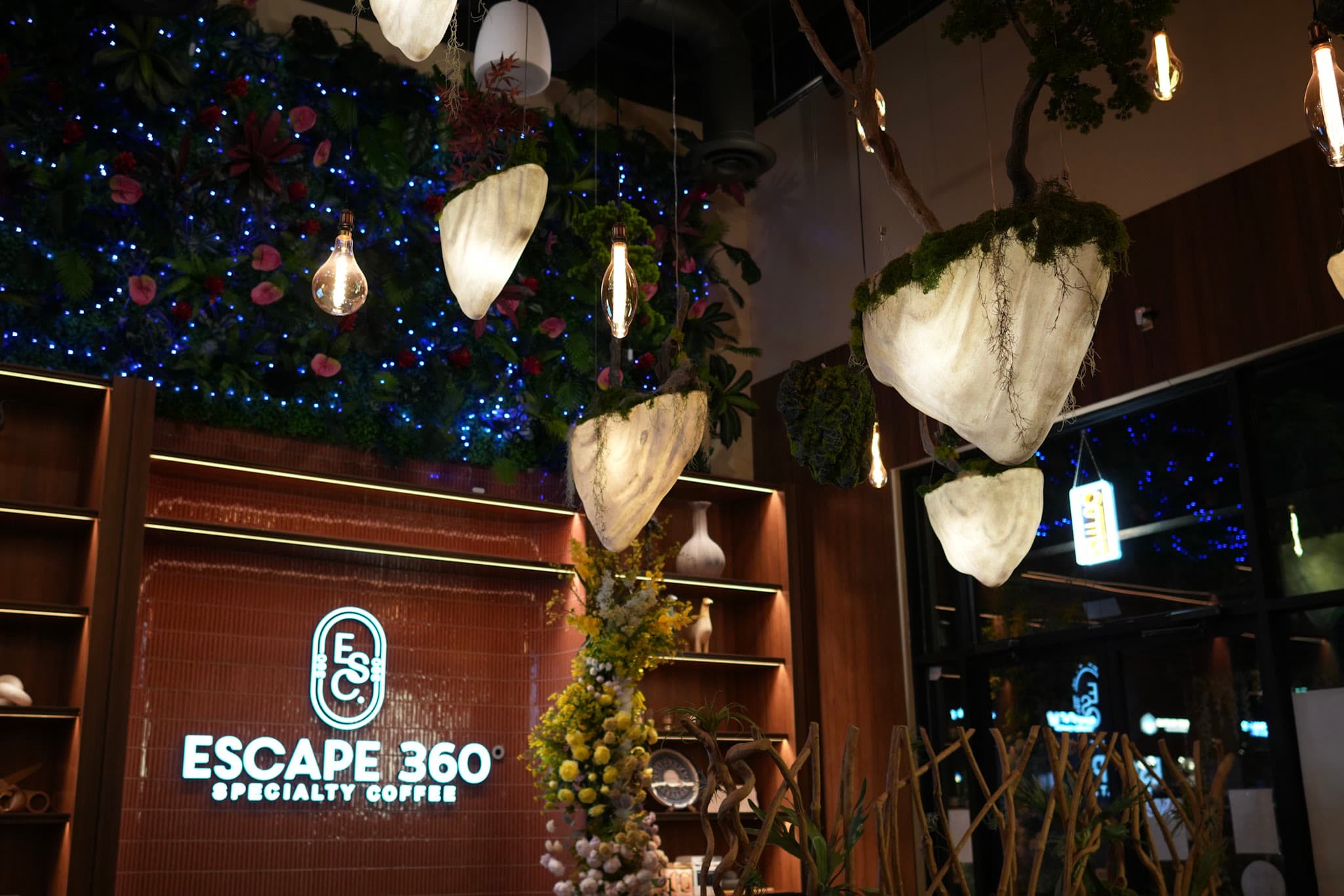 Escape 360 Carrollton — glowing pod lanterns, the living green wall, and the brand sign