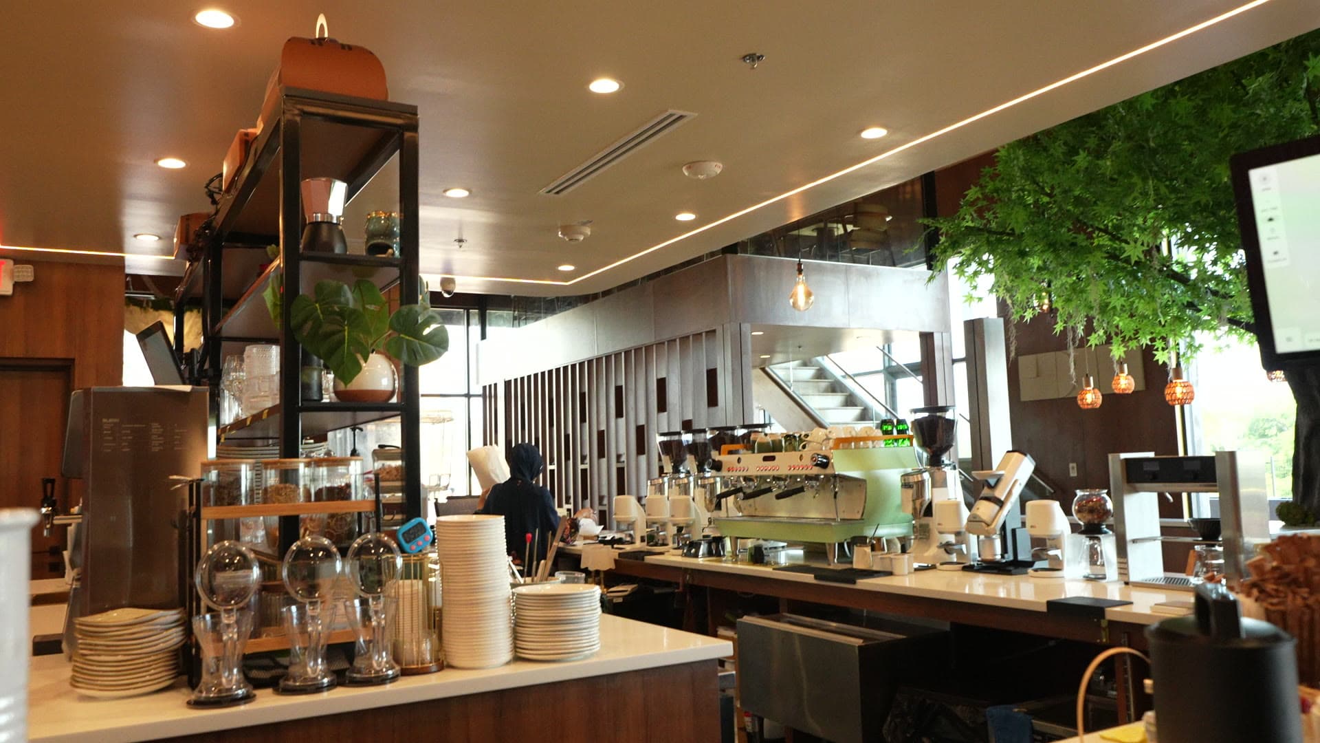 The espresso bar at Escape 360 Carrollton — mint-green machine beneath warm wood and greenery