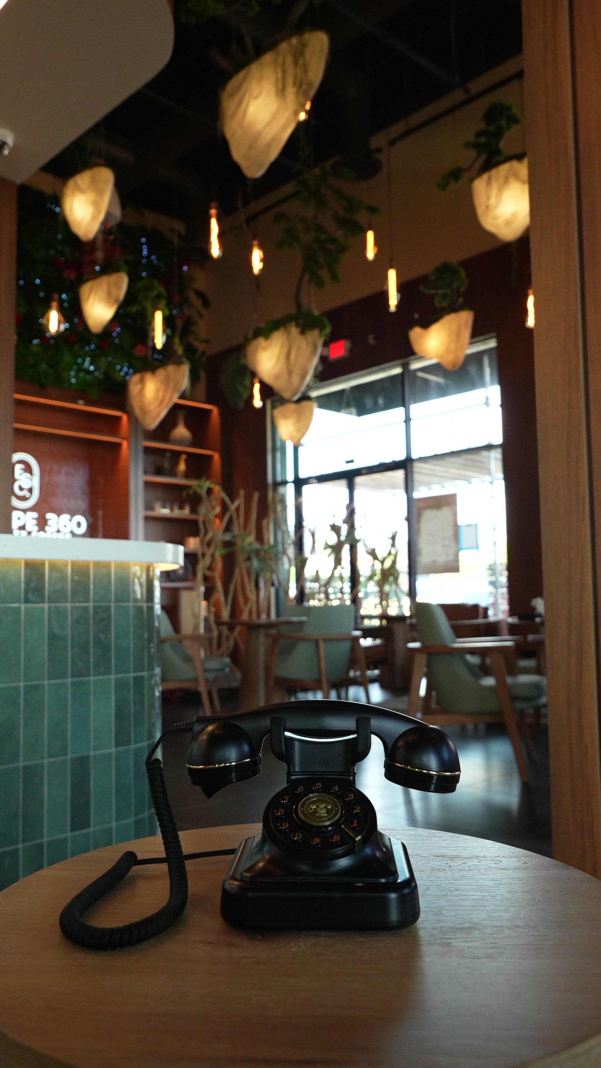 A vintage rotary phone resting on a wood table by the teal counter