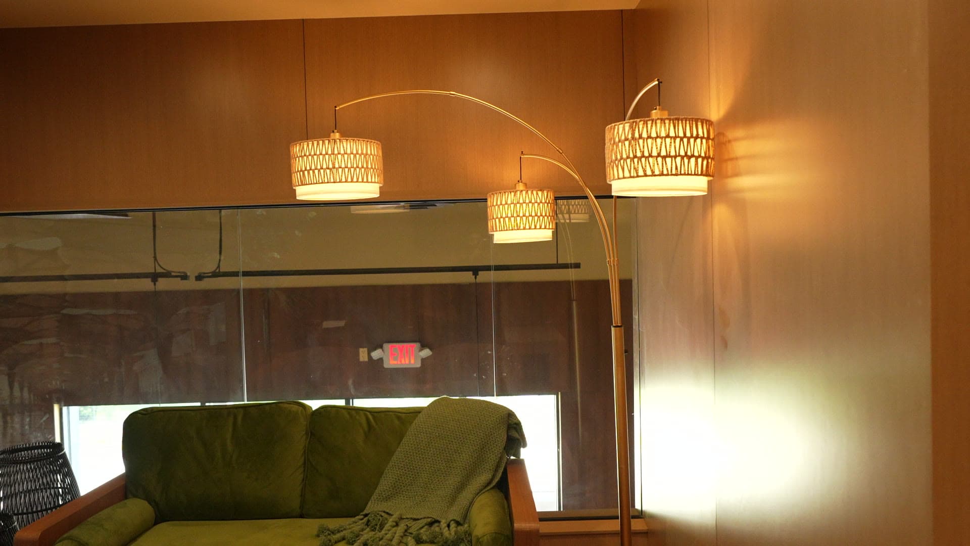 A cozy olive-velvet sofa beneath a woven arc floor lamp