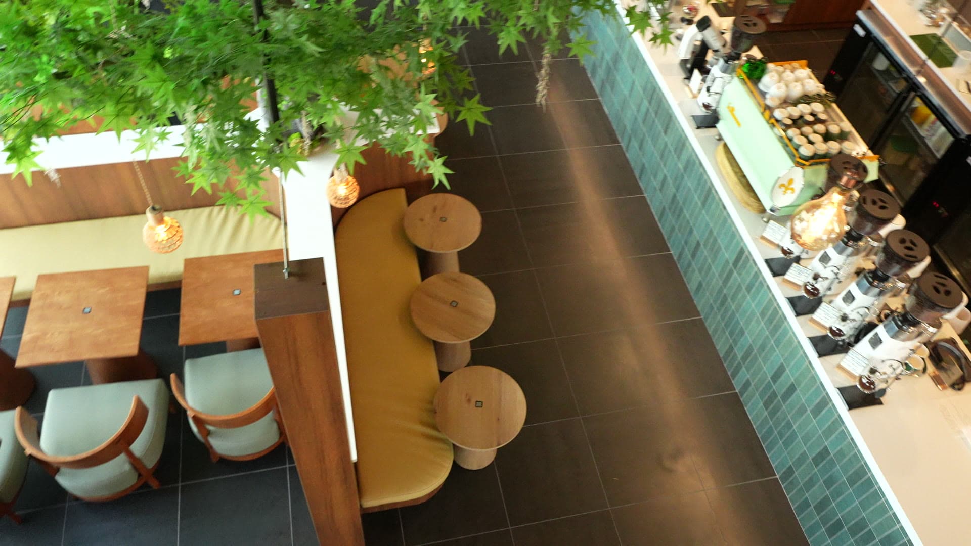 An elevated view of the banquette seating, round tables, and teal-tiled bar