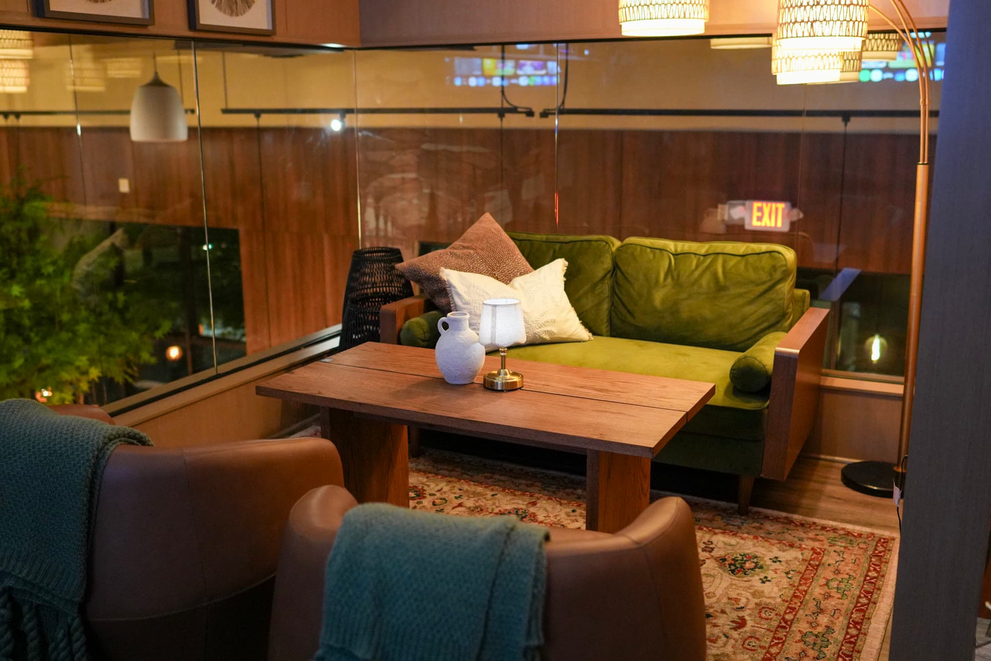 The Private Lounge Room at Escape 360 Carrollton — green velvet couch and leather chairs behind soundproof glass