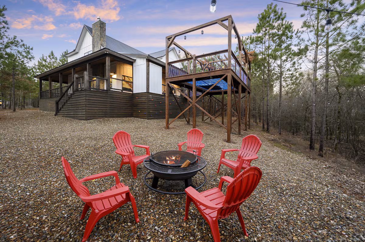 Red Adirondack chairs around the fire pit below the cabin